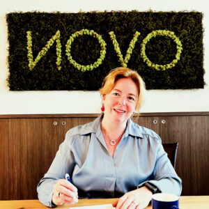 advocaat Femke van Velden zit aan tafel met achter haar het logo van Novo Advocatuur en Mediation
