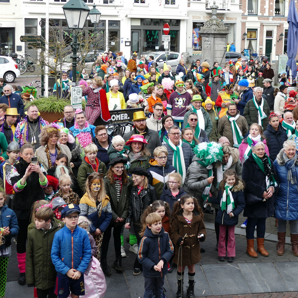 Carnavalvierders met groenwitte shawls op de Haagsemarkt in Princenhage