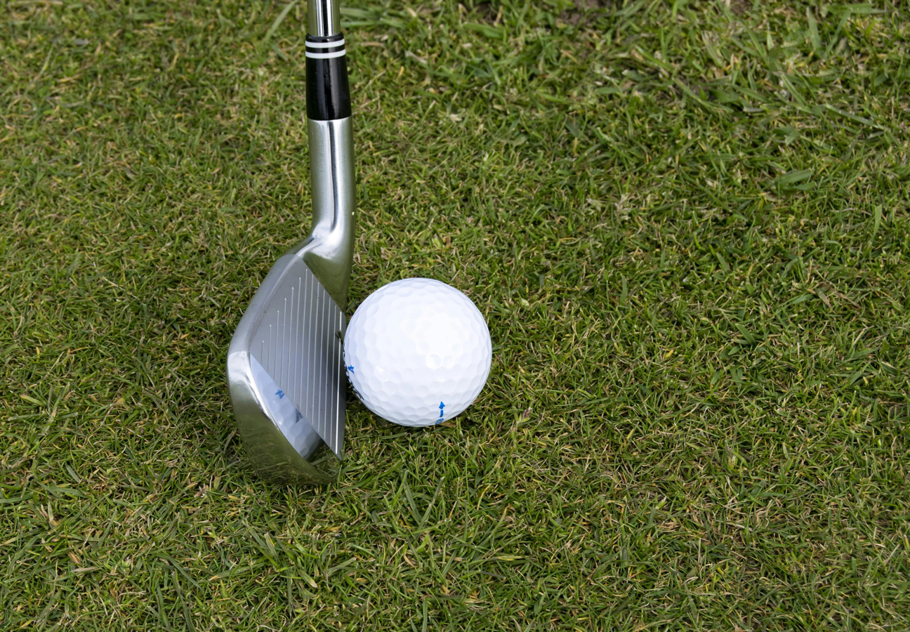 golfclub en golfbal op groen gras