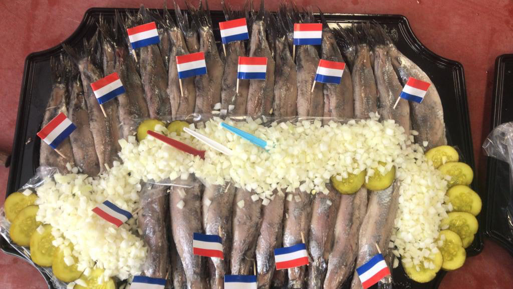 Een schaal met haring met Nederlandse vlaggetjes en uitjes