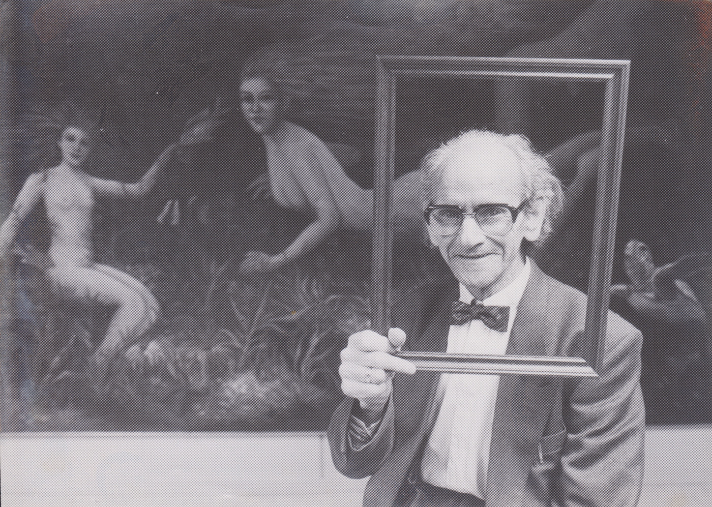 Theo Rasenberg staat voor een schilderij. De schilder houdt een schilderijlijst vast