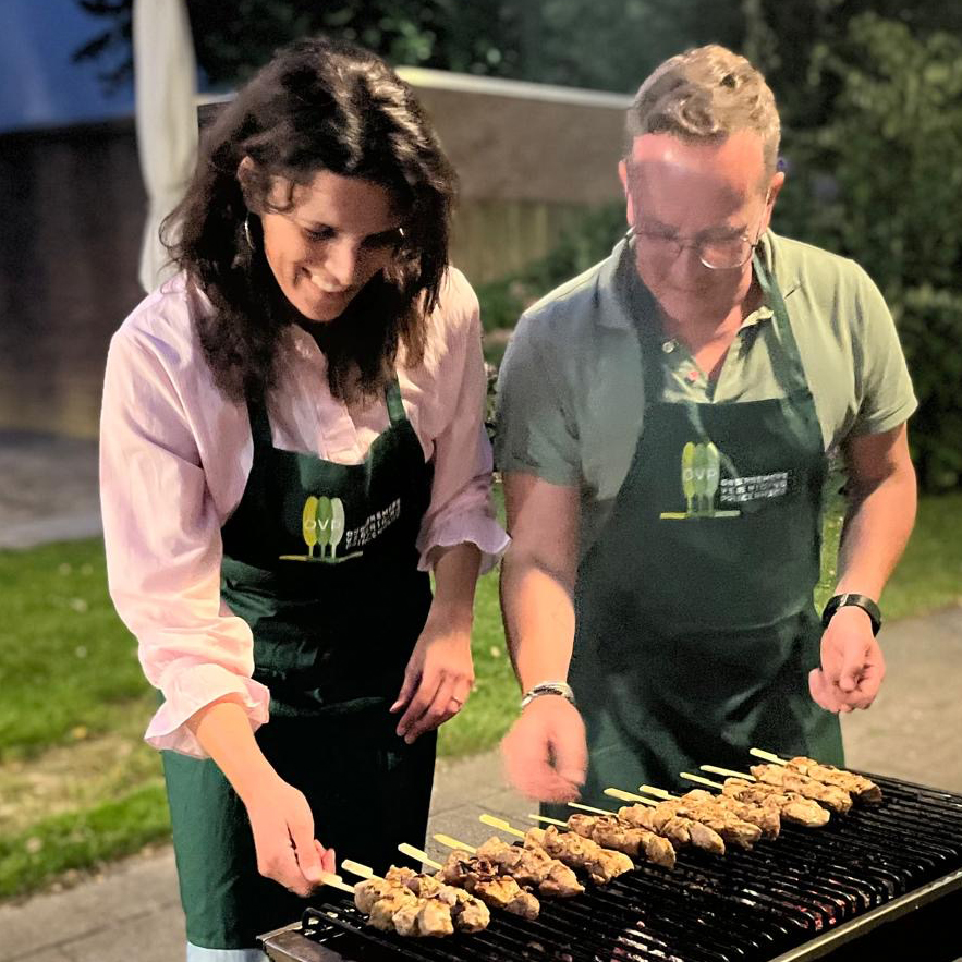ondernmers met koookschort leggen kipsatés op een barbecue