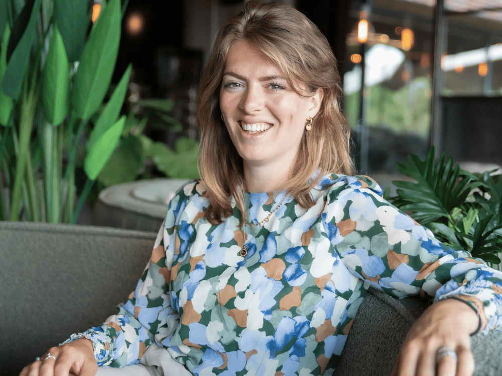 Katelijne van Tienhoven met een gebloemde blouse kijkt lachend in de camera
