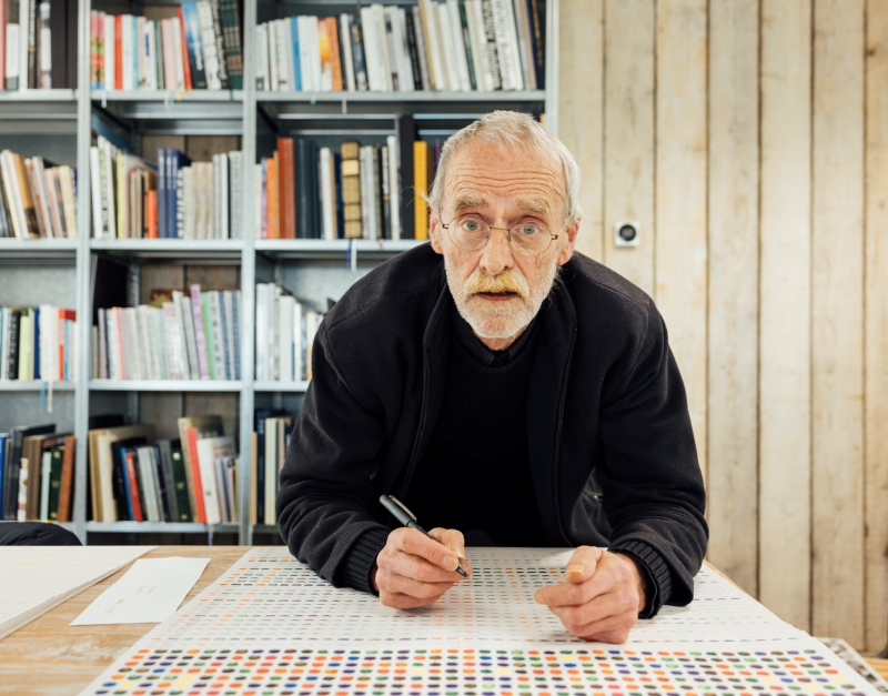 grafisch kunstenaar Henk Cornelissen aan het werk met pen en paier achter zijn tekentafel