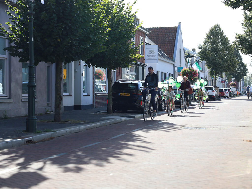 Kinderen komen met hun vader en moeder aan met fietsen versierd met groen en witte ballonnen.