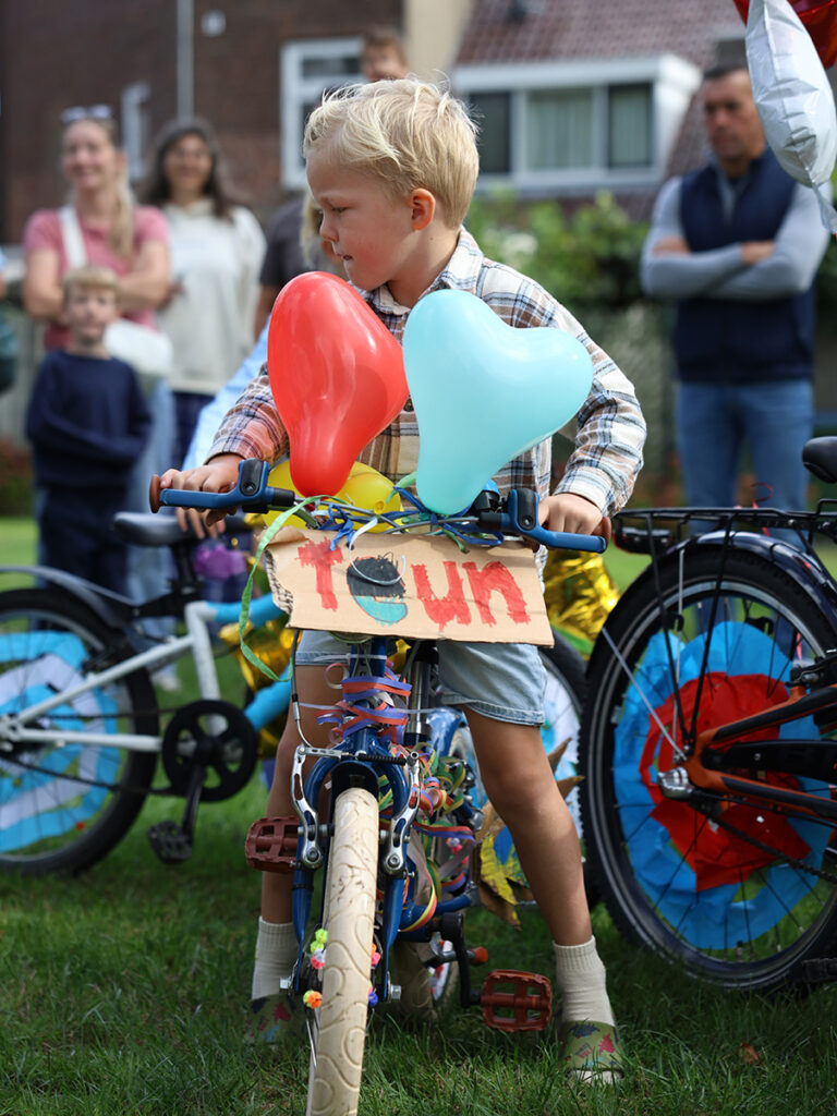 Jongen met een fiets met een bord 'Teun' met twee ballonnen in een hartvorm