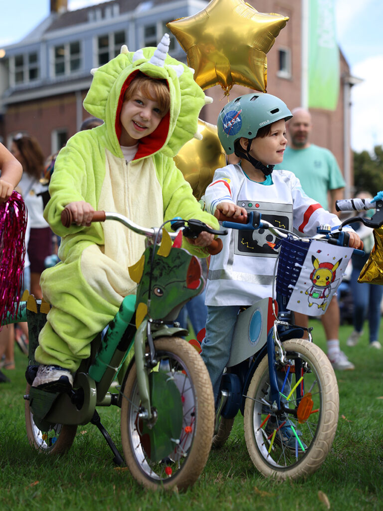 Twee jongens op hun fiets. Een jongen draagt een onesie van Yoshi.