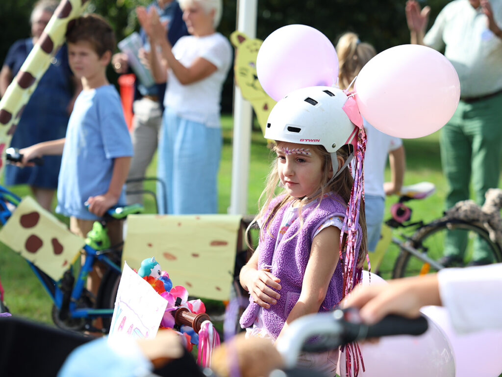 Meosje met 2 ballonnen aan haar fietshelm
