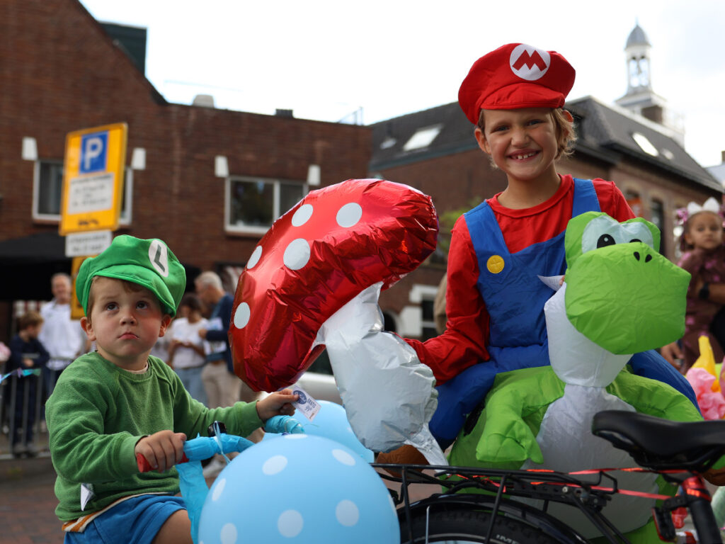 Twee kinderen verkleed als Mario en Luigi. Luigi zit op een driewieler.