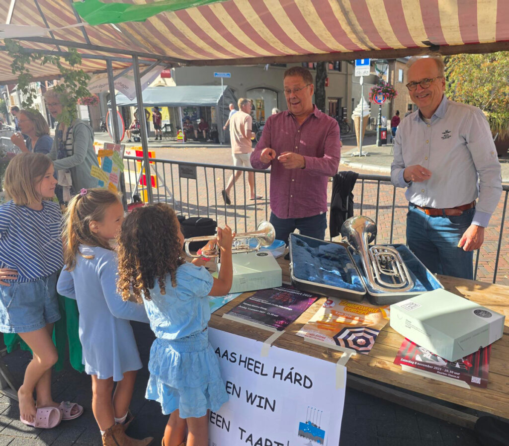 drie kinderen staan bij de kraam van Cecilia Princenhage en proberen zo hard mogelijk om een bariton te blazen