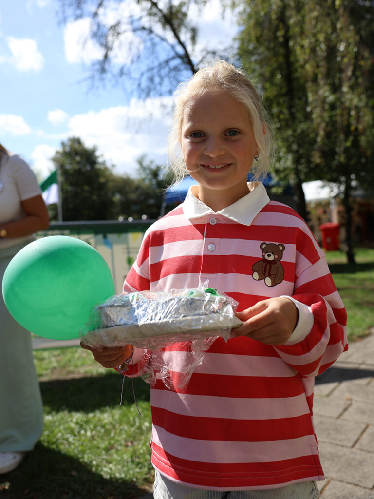 meisje houdt een groene ballon en bord vast met daarop een taart.