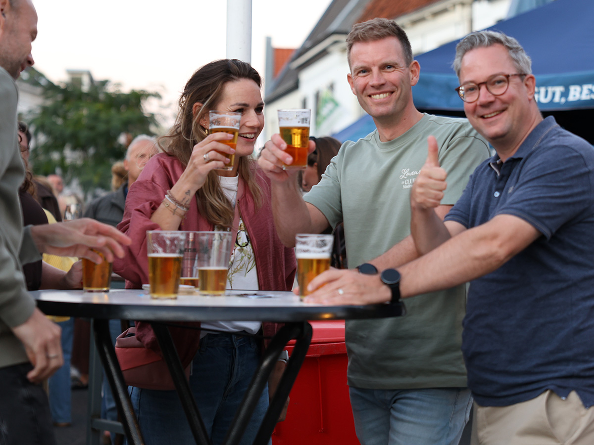 Drie bezoekers van Muziek & feest op de Haagsemarkt proosten met bier