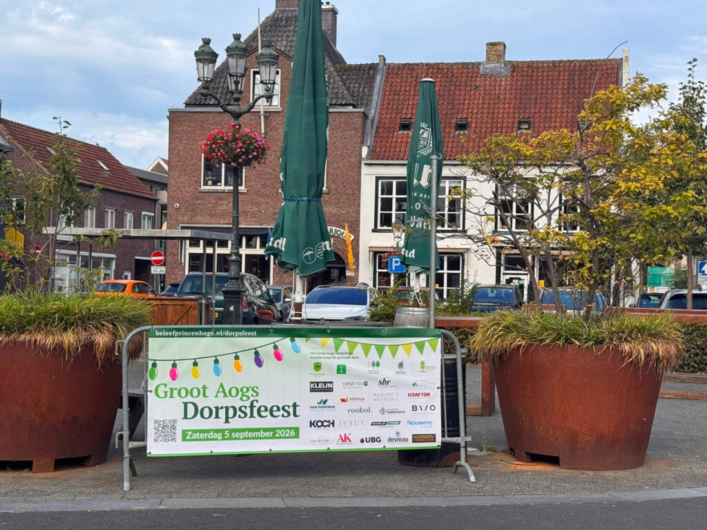 dranghek met spandoek van het Groot Aogs Dorpsfeest met logo's van sponsors